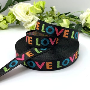 May include: Black woven ribbon with the word "LOVE" printed in rainbow colors.