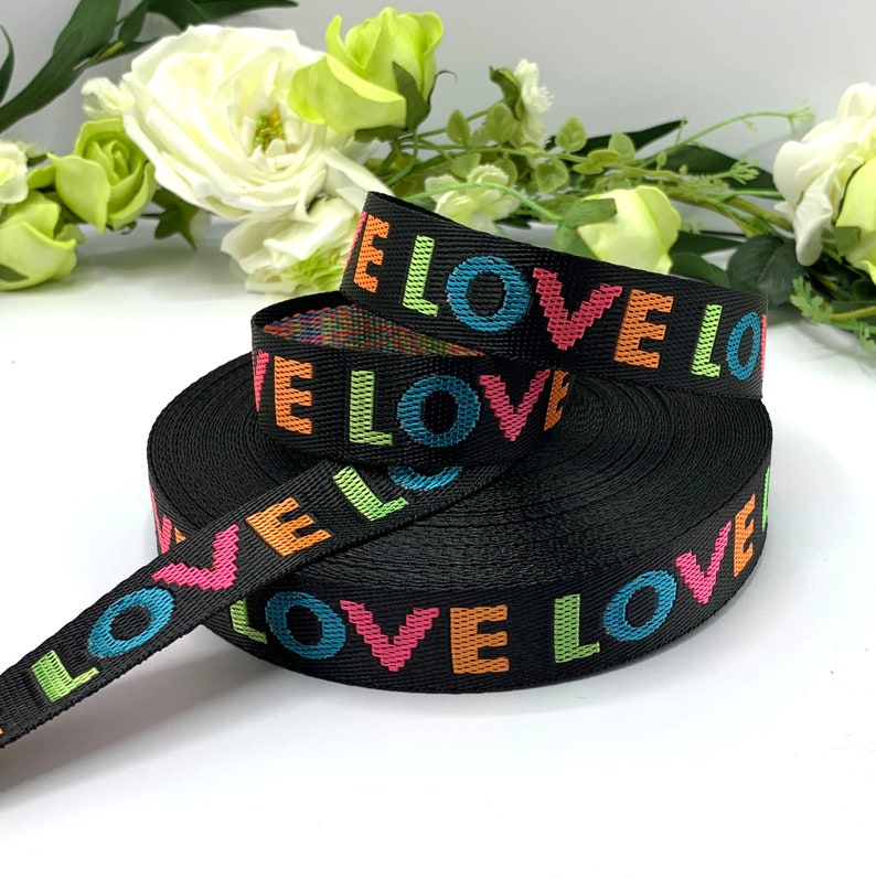 May include: Black woven ribbon with the word "LOVE" printed in rainbow colors.