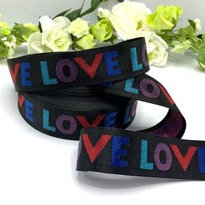May include: Black ribbon with the word "LOVE" repeated in colorful letters. The letters are red, blue, purple, and teal.