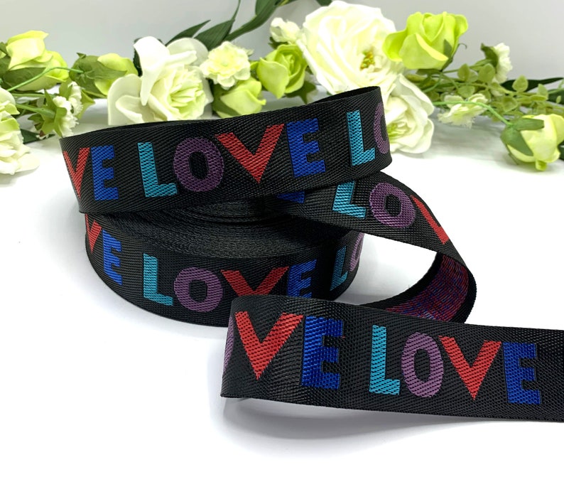 May include: Black ribbon with the word "LOVE" repeated in colorful letters. The letters are red, blue, purple, and teal.