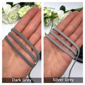 May include: Two close-up images of gray elastic cord. The first image shows a dark gray elastic cord. The second image shows a silver gray elastic cord.
