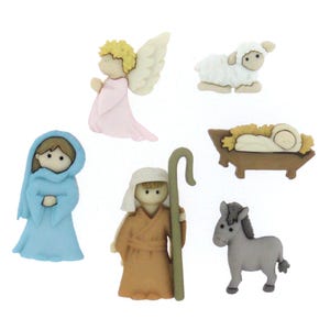 Könnte beinhalten: Eine Sammlung dekorativer Knöpfe zum Thema Weihnachten. Das Set enthält einen Engel in Rosa, ein Lamm, eine Figur in einem blauen Gewand, einen Hirten mit Stab, einen Esel und ein Baby in einer Krippe. Die Knöpfe sind in verschiedenen Farben.