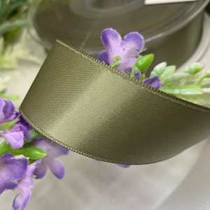 May include: A roll of sage green satin ribbon. The ribbon is smooth and has a subtle sheen.