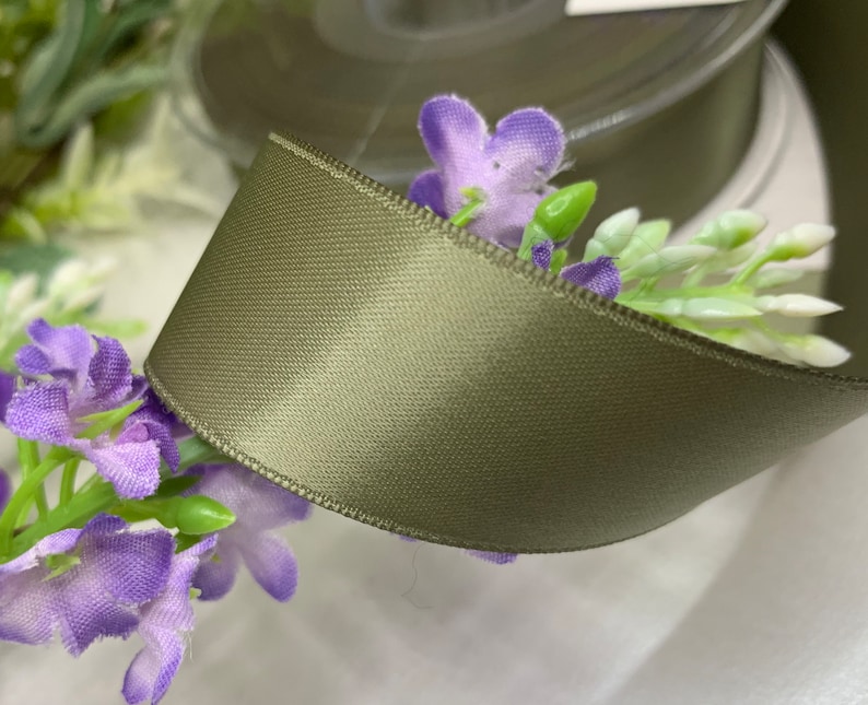 May include: A roll of sage green satin ribbon. The ribbon is smooth and has a subtle sheen.
