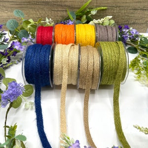 May include: Assortment of colorful jute twine spools in blue, red, orange, yellow, brown, and green. The twine is natural and has a rough texture.