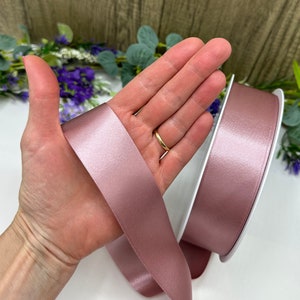 May include: A roll of dusty rose satin ribbon. The ribbon is soft and shimmery, ideal for adding a touch of elegance to any project.