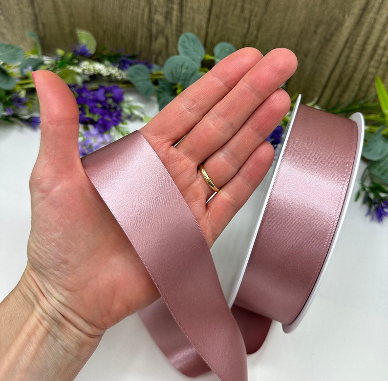 May include: A roll of dusty rose satin ribbon. The ribbon is soft and shimmery, ideal for adding a touch of elegance to any project.