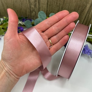 May include: A roll of dusty rose satin ribbon. The ribbon is 2.5 cm wide and has a soft, silky texture.