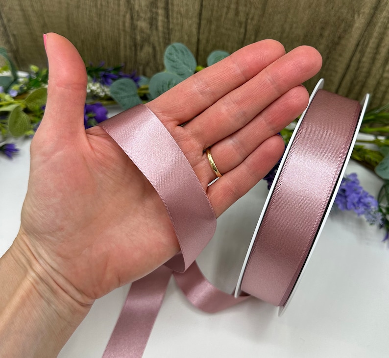 May include: A roll of dusty rose satin ribbon. The ribbon is 2.5 cm wide and has a soft, silky texture.