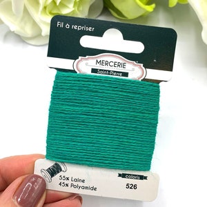 May include: A spool of green embroidery floss with the text "Fil &agrave; repriser" and "Mercerie Saint-Pierre" on the label. The label also indicates the floss is 55% wool and 45% polyamide and the color number is 526.