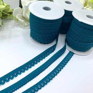 May include: Three spools of teal blue elastic trim with different patterns. The trim is on white spools and the trim is laid out on a white surface.