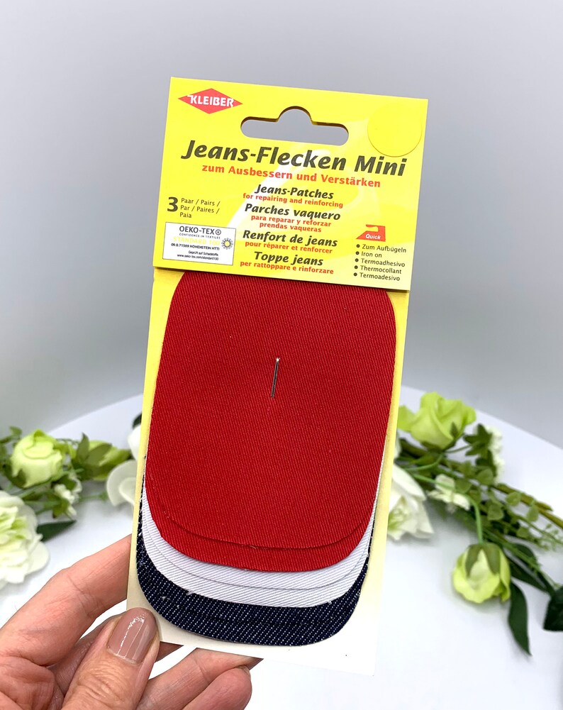 May include: A pack of three iron-on patches for repairing jeans. The patches are red, white, and blue denim. The packaging is yellow and has the text "Jeans-Flecken Mini" and "zum Ausbessern und Verst&auml;rken".