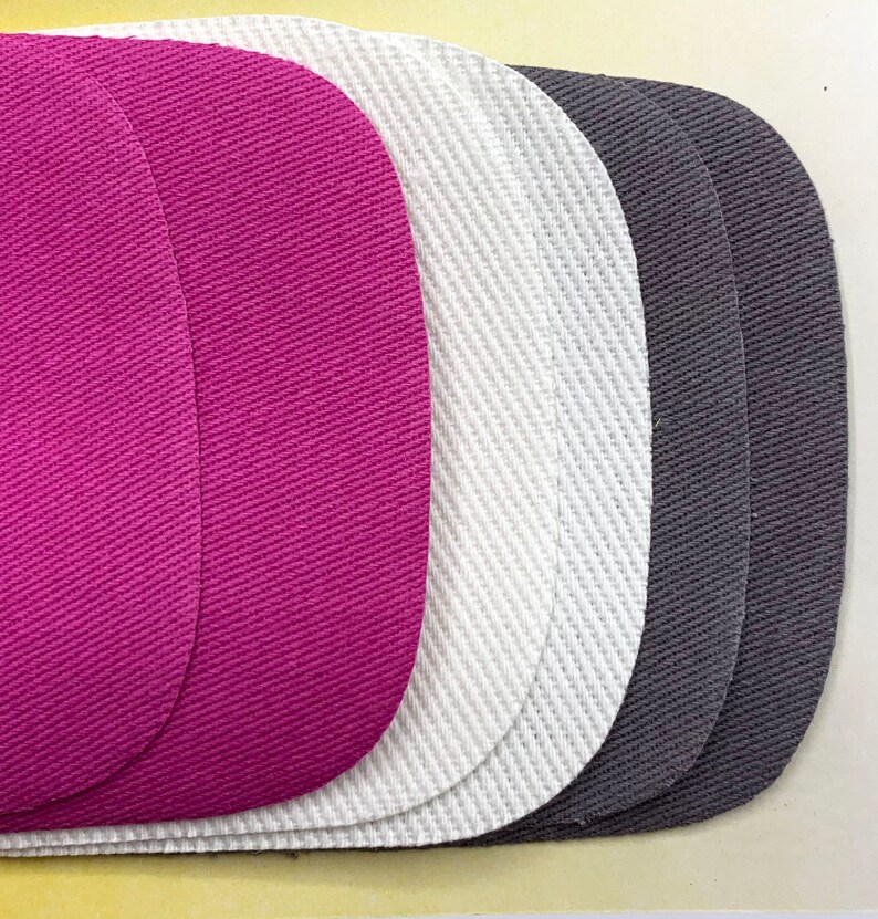May include: Three fabric patches in different colors: pink, white, and gray. The patches are oval-shaped and have a textured surface.