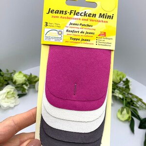 May include: A pack of three denim patches for repairing and reinforcing jeans. The patches are in pink, white, and gray. The packaging says "Jeans-Flecken Mini" and "Quick".