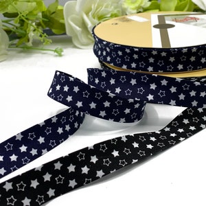 Peut inclure: Deux rouleaux de ruban en tissu à motif d'étoiles blanches. Un rouleau est bleu marine et l'autre est noir.