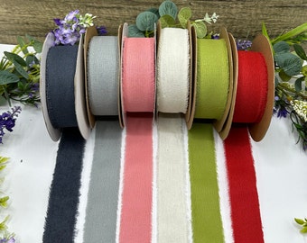 May include: Six spools of frayed ribbon in various colors, including black, gray, pink, white, green, and red. The ribbon is displayed on a wooden surface.