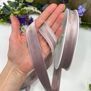 K&ouml;nnte beinhalten: Eine Rolle mauvefarbenes Samtband mit Satin-Kante. Das Band ist etwa 2,5 cm breit.