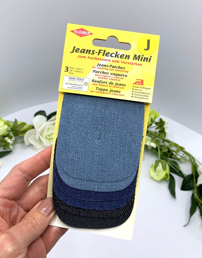 May include: A pack of three denim patches for repairing and reinforcing jeans. The patches are in different shades of blue and black. The packaging is yellow and has the text "Jeans-Flecken Mini" and "zum Ausbessern und Verst&auml;rken".