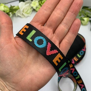 May include: Black woven elastic ribbon with the word "LOVE" repeated in rainbow colors.