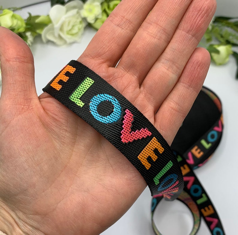 May include: Black woven elastic ribbon with the word "LOVE" repeated in rainbow colors.