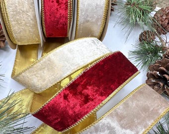 Op de afbeelding: Drie rollen fluwelen lint in de kleuren crème, dieprood en champagne. Elk lint is voorzien van een metallic gouden draadrand. De linten zijn in een trapsgewijze opstelling geplaatst, wat de zachte textuur en de gouden rand benadrukt.