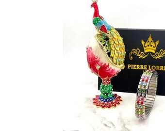 May include: A colorful jeweled peacock figurine with a black box that says "Pierre Lorre" and a multi-colored jeweled bracelet.