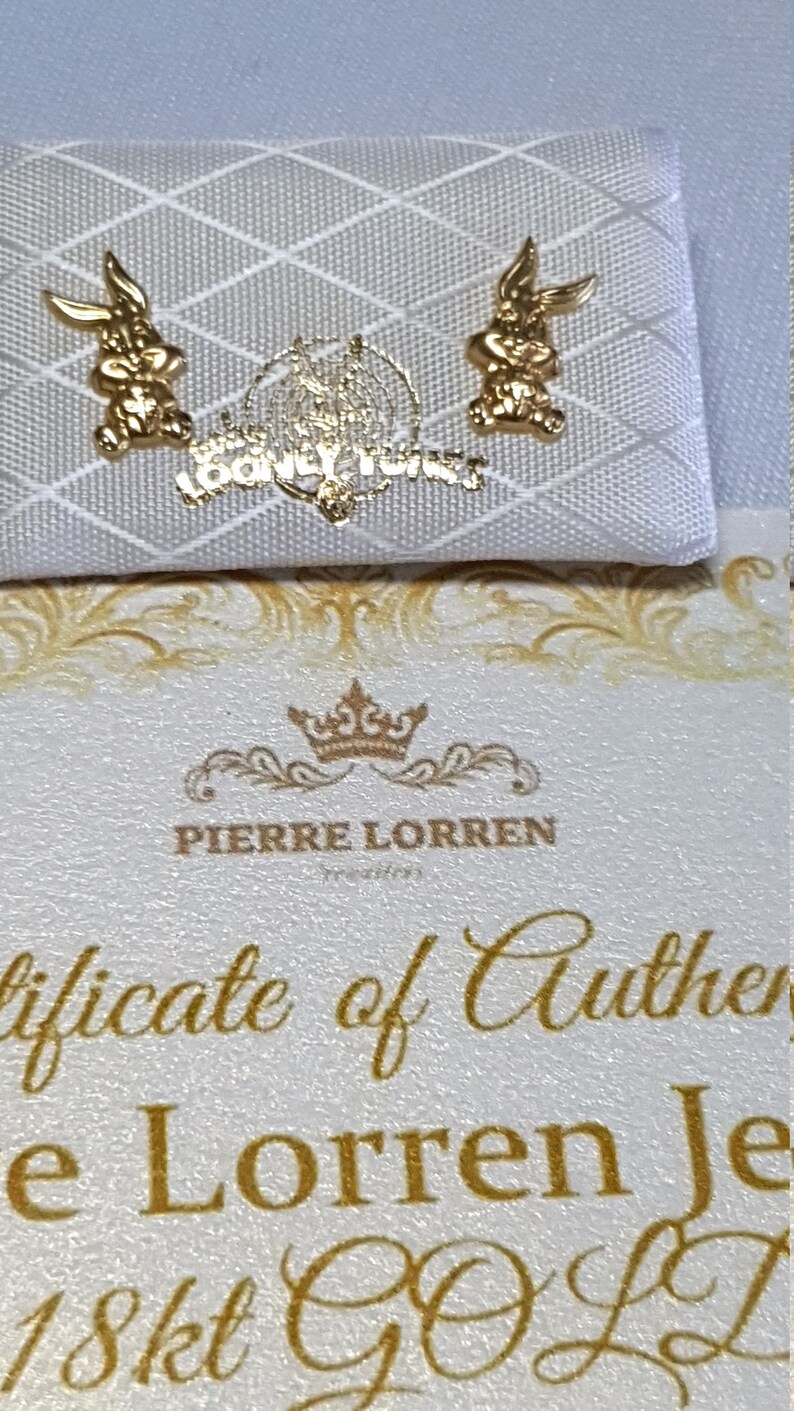 May include: A white certificate of authenticity for a pair of 18kt gold earrings featuring a Bugs Bunny design. The certificate is from Pierre Lorren.