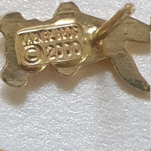 May include: Gold-toned metal earrings with a stylized design. The earrings have a post back closure and are marked "JAPAN 2100".