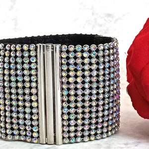 May include: A black elastic bracelet with a silver clasp and a row of iridescent rhinestones.