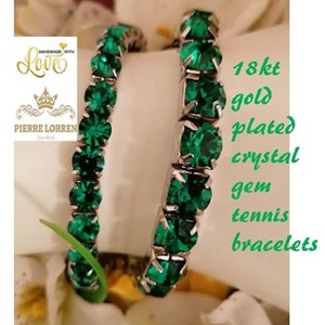 May include: Two 18kt gold plated tennis bracelets with emerald green crystal gems. The bracelets are 6mm and 8mm wide.
