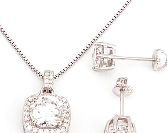 May include: A silver necklace and earrings set with a square pendant featuring a large, clear, round stone surrounded by smaller stones.