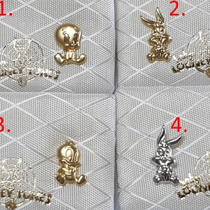 May include: Four pairs of gold and silver Looney Tunes earrings. The earrings feature Bugs Bunny and Tweety Bird.