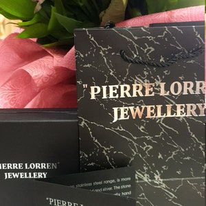 Puede incluir: Un certificado de autenticidad en blanco y negro para joyer&iacute;a Pierre Lorren. El certificado est&aacute; sobre un fondo negro con texto blanco. El texto dice "Pierre Lorren" Joyer&iacute;a Certificado de autenticidad.