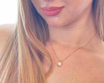 Può includere: Una donna indossa una collana a catena d'oro con un ciondolo rotondo di diamanti.