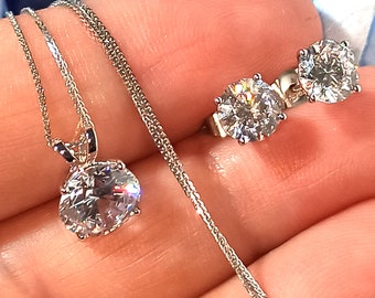Può includere: Una collana d'argento con un ciondolo rotondo di cristallo trasparente e orecchini abbinati con pietre rotonde di cristallo trasparente.