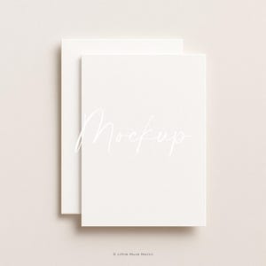 Op de afbeelding: Twee crèmekleurige rechthoekige kaarten, waarvan er één de andere lichtjes overlapt, tegen een neutrale achtergrond. Het woord "Mockup" is in een sierlijke, cursieve lettertype op de bovenste kaart geschreven. De onderkant van de afbeelding bevat de tekst "Little Muse Mocks".