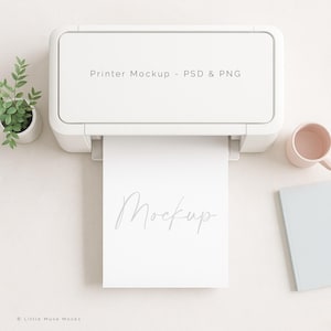 May include: A white printer mockup with the text "Printer Mockup - PSD & PNG" at the top. A sheet of paper with the word "Mockup" is coming out of the printer. A small potted plant, a pink mug, and a light blue notebook are also in the image.