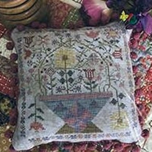 May include: A hand-stitched needlepoint pillow featuring a colorful floral design with a central vase and a geometric pattern in the background.