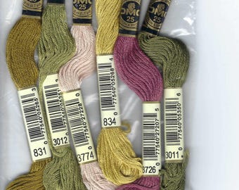 Puede incluir: Primer plano de ocho carretes de hilo para bordar en varios colores, incluyendo verde, amarillo, rosa y marrón. Cada carrete tiene una etiqueta con el logotipo de DMC y el número del color. Las etiquetas también incluyen códigos de barras y el texto "ULINE SPEC" y "COTTON A BRO".