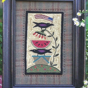 May include: A framed needlepoint artwork depicting a black bird perched on a watermelon slice, with another black bird perched on a small table below. The top of the artwork features a small American flag.