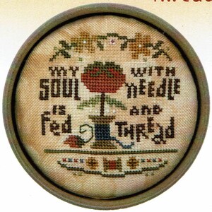 Könnte beinhalten: Ein Kreuzstich-Stickmuster in einem ovalen Rahmen mit dem Text "My soul is fed with a needle and thread". Das Design zeigt eine rote Blume mit grünen Blättern und eine Spule mit Garn.