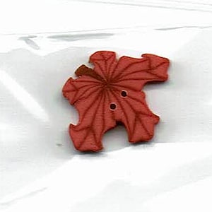 May include: A red plastic button shaped like a leaf with a detailed vein pattern. The button has two holes for sewing.