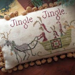 May include: Rectangular cream-colored pillow with the words "Jingle Jingle" embroidered in red. The pillow features a cross-stitch design of a reindeer pulling a sleigh with two figures. The pillow is trimmed with small, tan pom-poms.