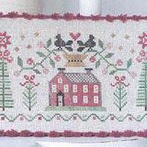 May include: Cross stitch pattern featuring a red house with white windows and a black chimney, two black birds perched on a brown pot, and two green trees with red flowers. The design is surrounded by a red scalloped border.