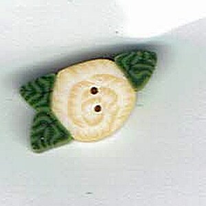 May include: A white button with a flower design and two brown buttons. The flower has green leaves.