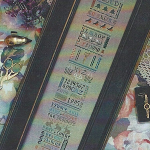 May include: A framed cross-stitch sampler with a black frame and a white background. The sampler features a variety of colorful stitches and designs, including letters, numbers, and a small tree. The text on the sampler reads "8888888 α ABCD 無盒魚 SLMNOP  rstuvw XXZ  1234567 690CAZ 1995 xsnore aux the showers Reer count 0440019 Shining KOUT'S HZ SFZ".