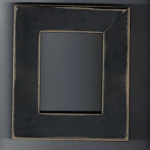 May include: A rectangular black picture frame with a distressed finish. The frame has a dark, matte appearance with a lighter, golden-brown trim along the inner and outer edges. The frame is empty.