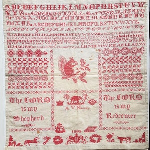 Puede incluir: Antiguo bordado rojo y crema con alfabeto, números y motivos decorativos. Presenta una ardilla, el texto "The LORD is my Shepherd" y "The LORD is my Redeemer", y la fecha 1885.