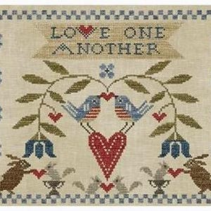 May include: Cross-stitch sampler with the text "LOVE ONE ANOTHER" above a design featuring two blue birds facing each other, a large red heart, and two rabbits. The design includes green leaves, blue flowers, and small red hearts.