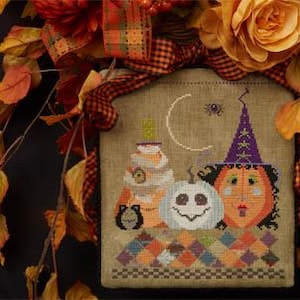 Pode incluir: Um bordado de ponto cruz que apresenta uma cena de Halloween caprichosa com uma bruxa, uma abóbora esculpida e uma pilha de abóboras. O fundo é um mosaico de quadrados coloridos.